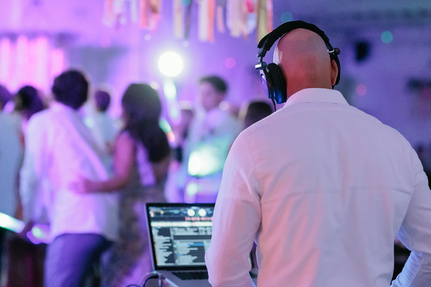 DJ Jake mixing music while guests dance at a Utah wedding reception